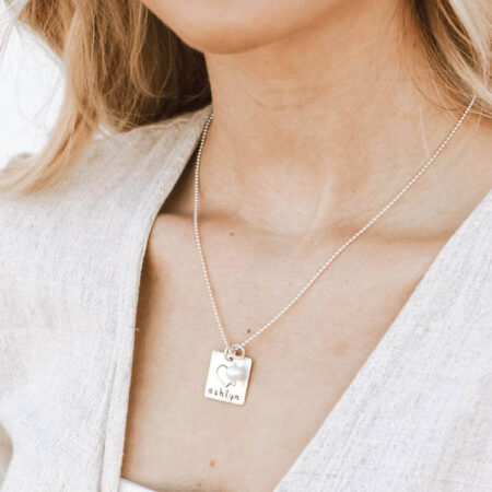 A sterling silver square with a small sterling heart fused on top, hand-stamped with a name or message