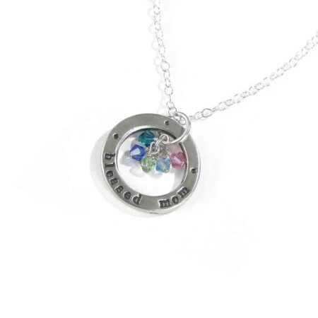 A sterling silver circle hand stamped with "blessed mom" along with kids birthstones. Perfect gift for a mom