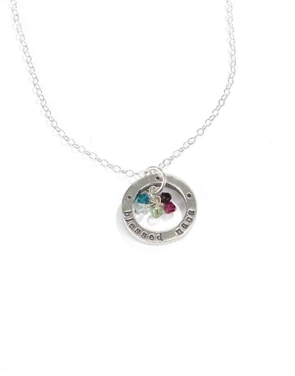 A sterling silver circle hand stamped with "blessed nana" along with grand kids birthstones. Perfect gift for a grandma