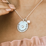 Dainty heart in the middle of the circle charm along with a hanging pearl. Personalize it by getting name engraved.