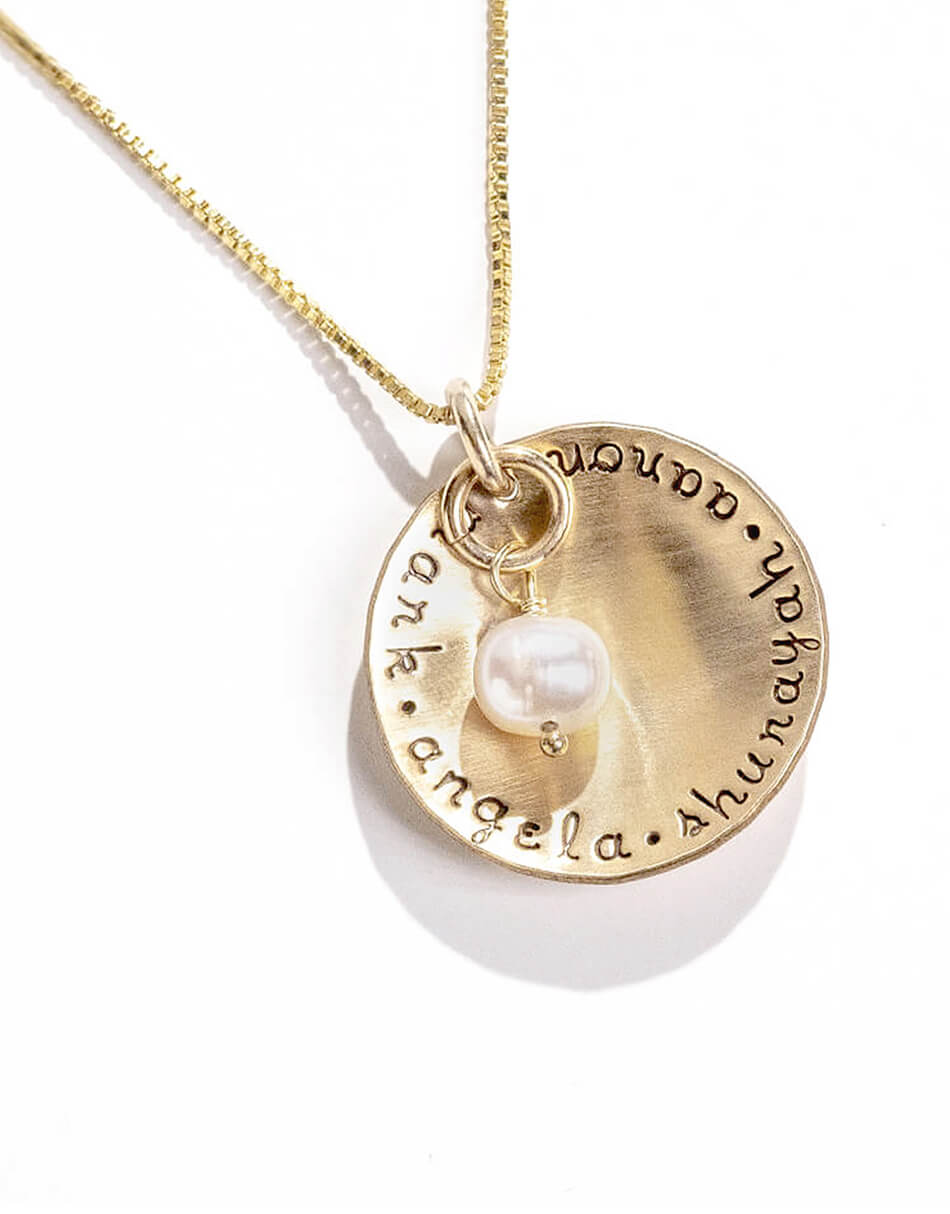A gold-filled disc with hand stamped names and a fresh water pearl. Perfect personalized jewelry for gift